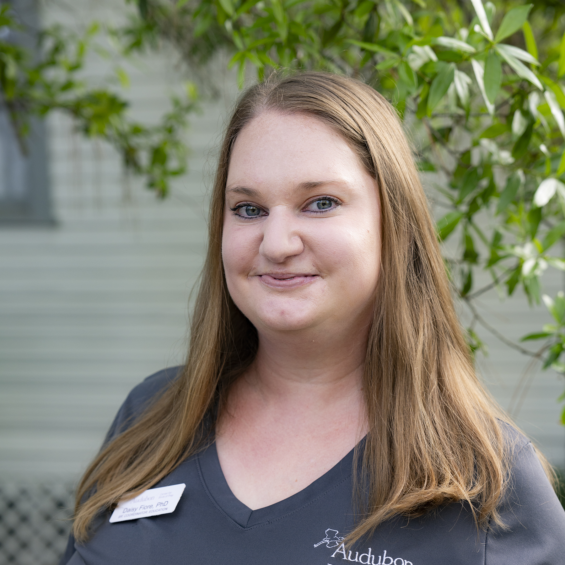 A portrait of a woman with light brown hair wearing a gray Audubon shirt.
